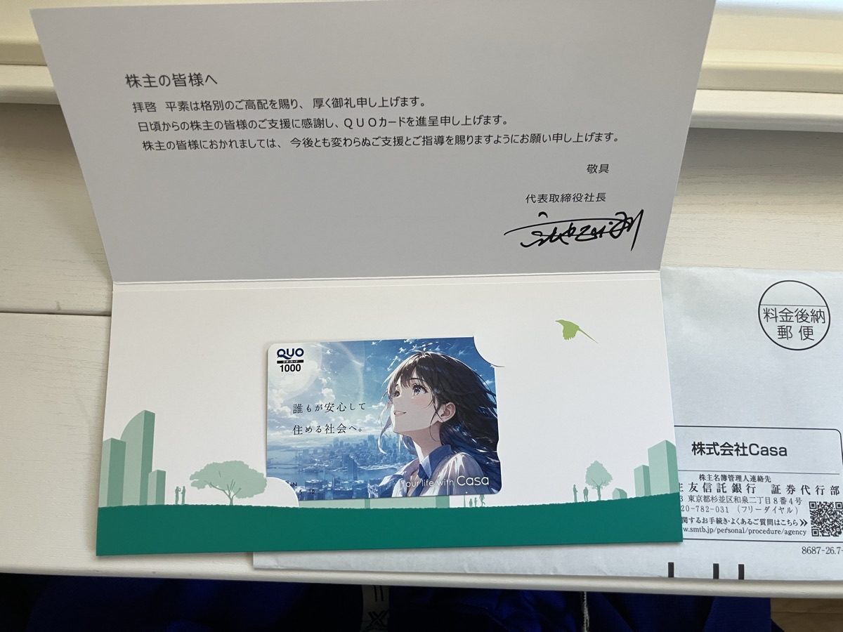 Casaから届いた株主優待。社長の直筆サイン入りのあいさつ状と、「誰もが安心して住める社会へ。」と書かれたQUOカード1,000円分が緑の台紙に入っている