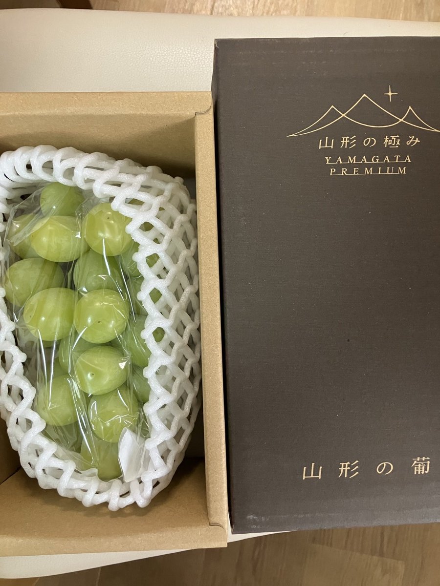 ヒューリックの株主優待で届いた山形のシャインマスカット。白いネットに包まれた房と、「山形の極み」と書かれた黒い箱