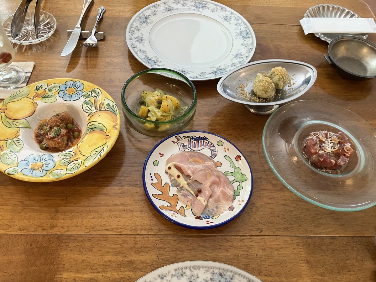 イタリアンのランチコースの前菜。生ハム、マグロのタルタル、ライスコロッケなどが、かわいい絵柄のお皿に並んでいる