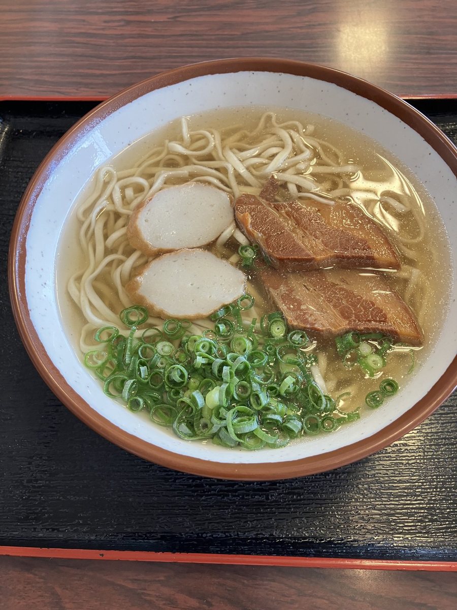 ランチに食べた沖縄そば。黒いお盆にのった丼に、澄んだスープと平打ちの麺、三枚肉2枚とかまぼこ2枚、たっぷりの小ねぎ
